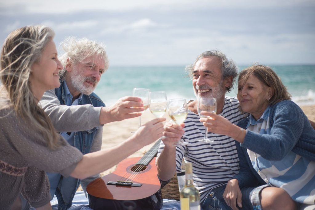 Four older friends laughing and toasting with glasses of wine